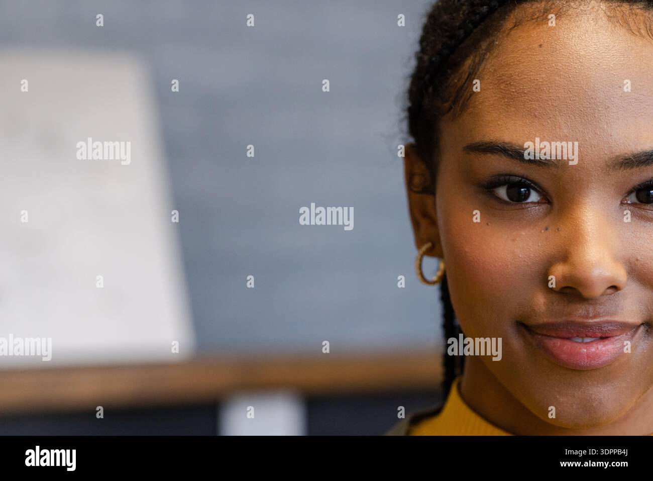 Femme afro-américaine posant en studio près de la toile portant un col roulé moutarde montrant des cheveux tressés Banque D'Images