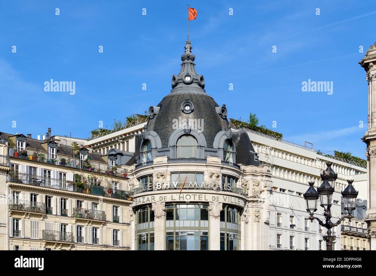 Paris, France - 27 avril 2022 : le dôme et la façade supérieure du grand magasin le BHV Marais sont visibles, avec des enseignes bien en vue indiquant « LE BHV/MARAIS » et « BAZAR DE L'HÔTEL DE VILLE », avec des détails architecturaux et un drapeau sur le dessus. Banque D'Images