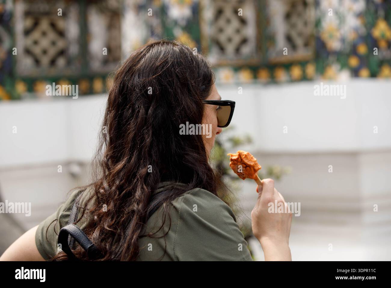 BANGKOK, THAÏLANDE-21 janvier 2026 : touriste femme explorant Wat Thai, tenant une crème glacée à la main, profil latéral Banque D'Images