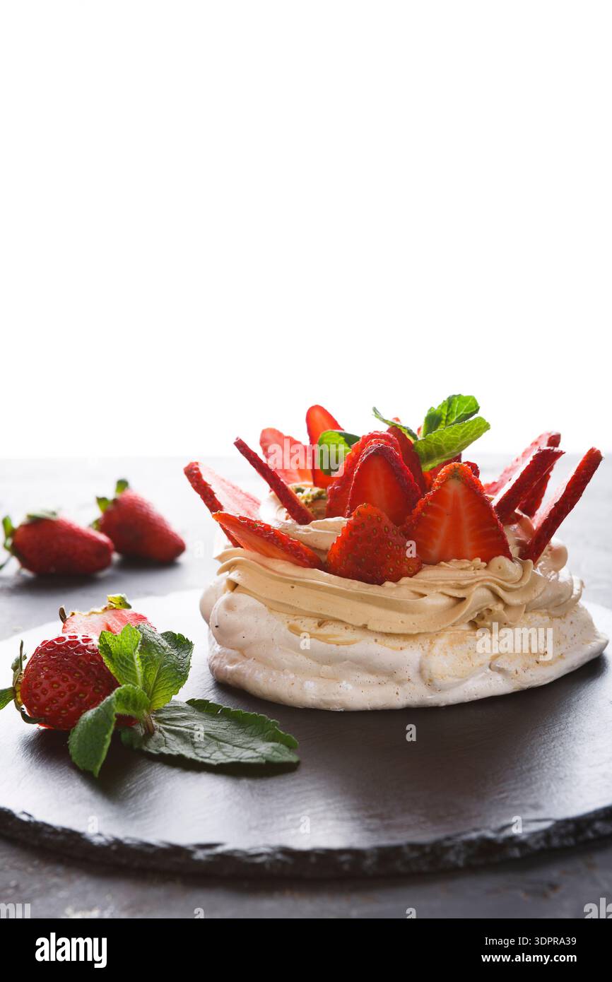 Dessert aux fraises avec feuilles de menthe sur une assiette sombre dans un cadre lumineux Banque D'Images