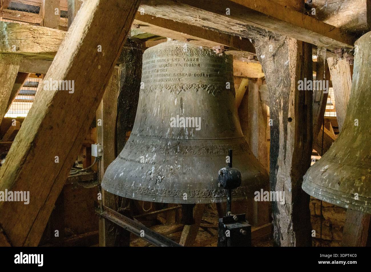 Eglise Saint Martin, France - 23 juillet 2020 : une grande cloche d'église en métal avec une inscription est visible parmi les poutres en bois et les structures de support à l'intérieur du clocher de l'Eglise Saint Martin. Banque D'Images