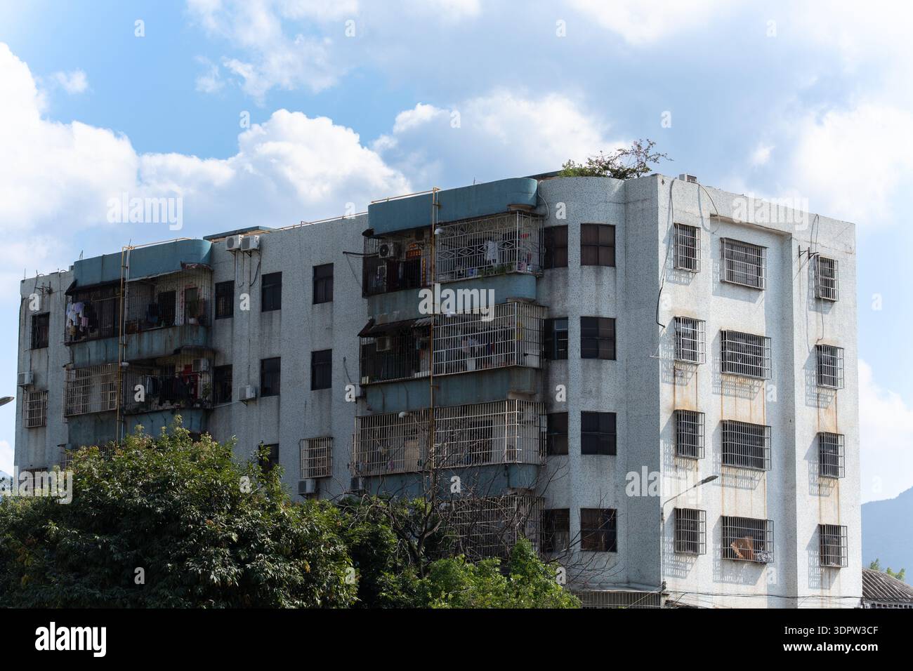 Immeuble d'appartements à plusieurs étages vieilli avec balcons rouillés sous le ciel nuageux dans la zone urbaine Banque D'Images