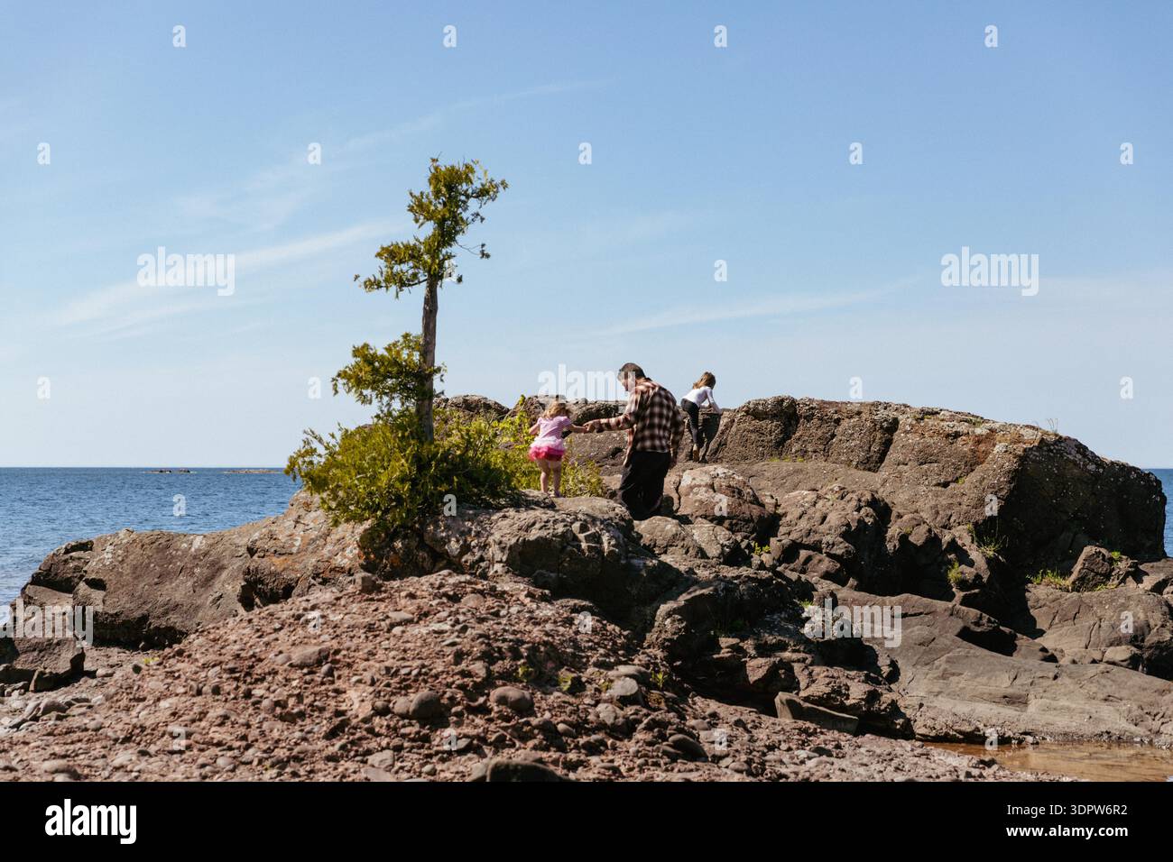 Famille jouant le long de la rive rocheuse du lac supérieur Banque D'Images