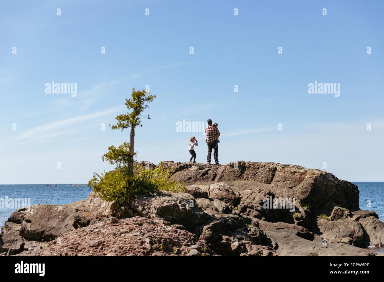 Famille jouant le long de la rive rocheuse du lac supérieur Banque D'Images