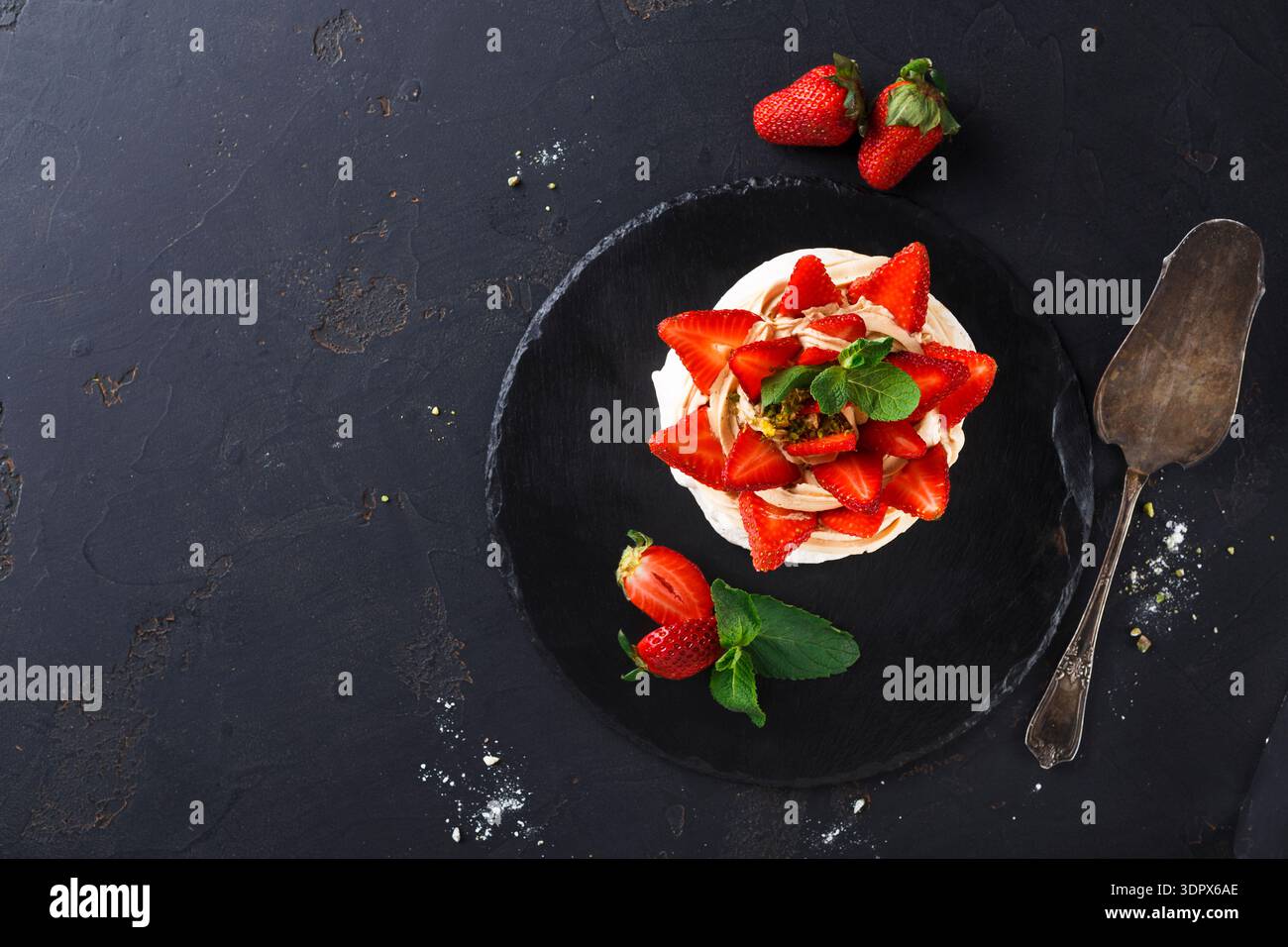 Fraises fraîches sur un dessert superposé avec des feuilles de menthe sur un fond sombre Banque D'Images