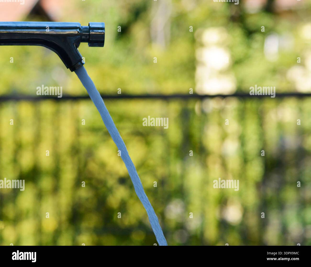 robinet de parc public avec l'eau sortant et le fond vert est flou Banque D'Images