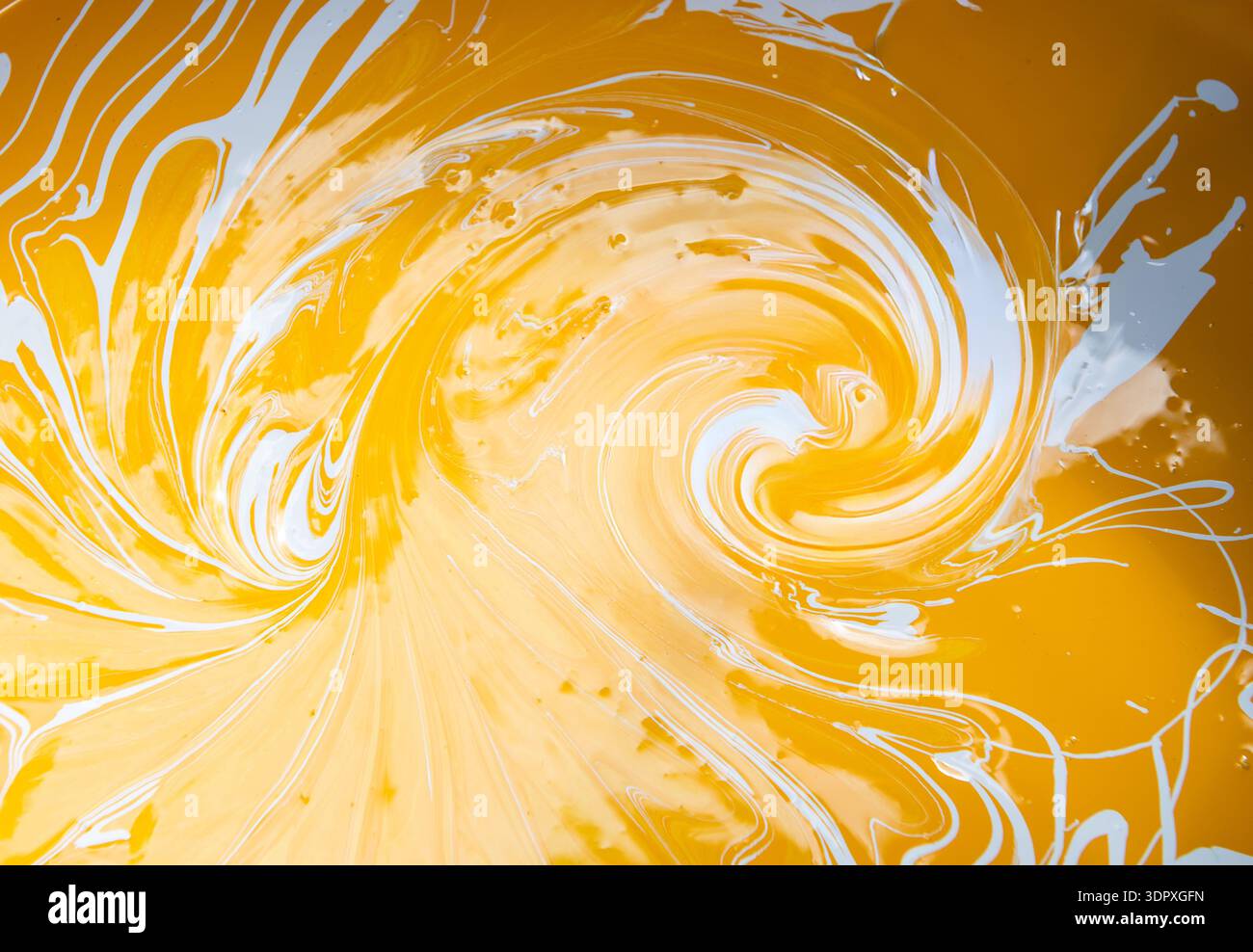 Peinture d'art fluide abstrait dans les peintures acryliques, peintures tourbillonnantes, couleurs jaune or et blanc créant Banque D'Images