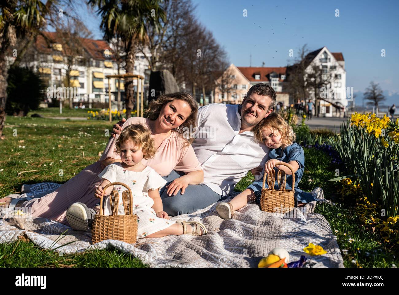 Une famille joyeuse profite d'un pique-nique de Pâques en plein air au printemps. Avec le soleil brille, parents et enfants sont rassemblés sur une couverture avec Pâques Banque D'Images