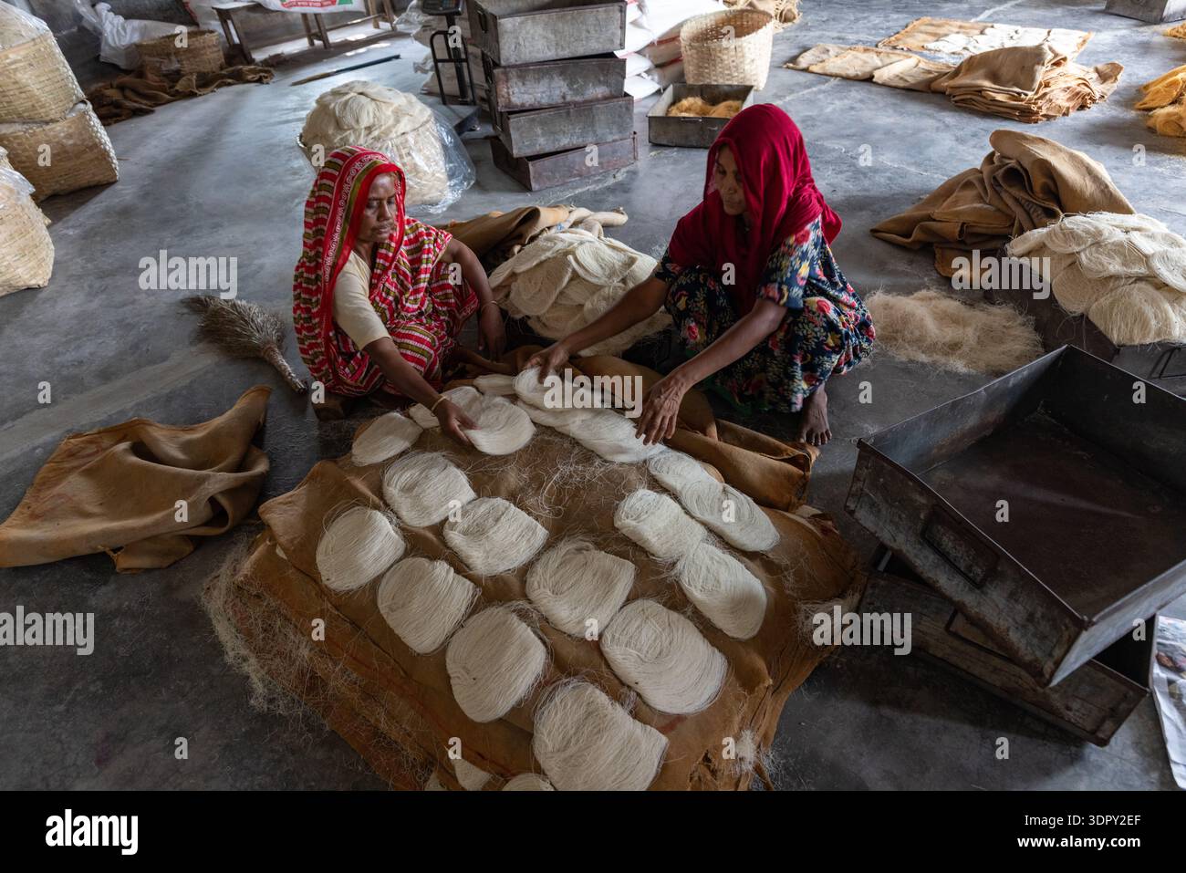 Bogura, Bangladesh - 17 avril 2022 : vue de femmes façonnant méticuleusement des morceaux de pâte blancs et circulaires sur fond contrasté de jute an grossier Banque D'Images