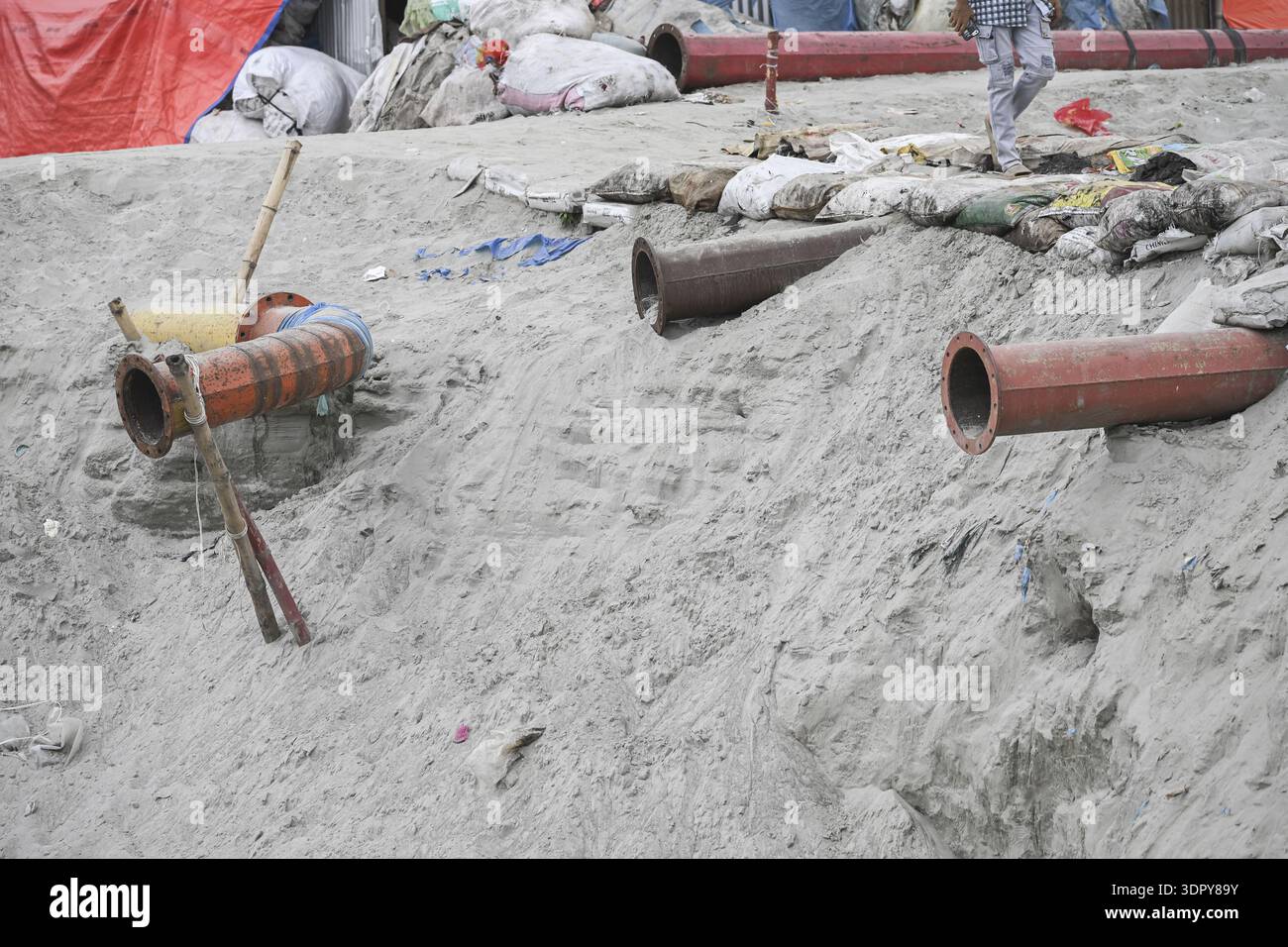 Dhaka, Bangladesh - 09 septembre 2025 : vue de grands tuyaux en terre cuite reposant sur un sol sablonneux, au milieu des débris dispersés et de la présence humaine subtile, UEDN Banque D'Images