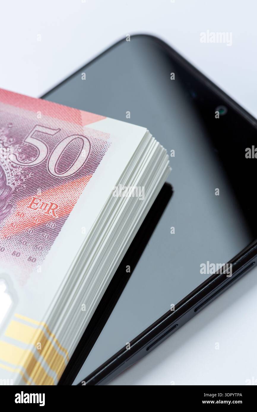 Gros plan d'une pile de billets de cinquante livres sur un téléphone portable. Banque D'Images