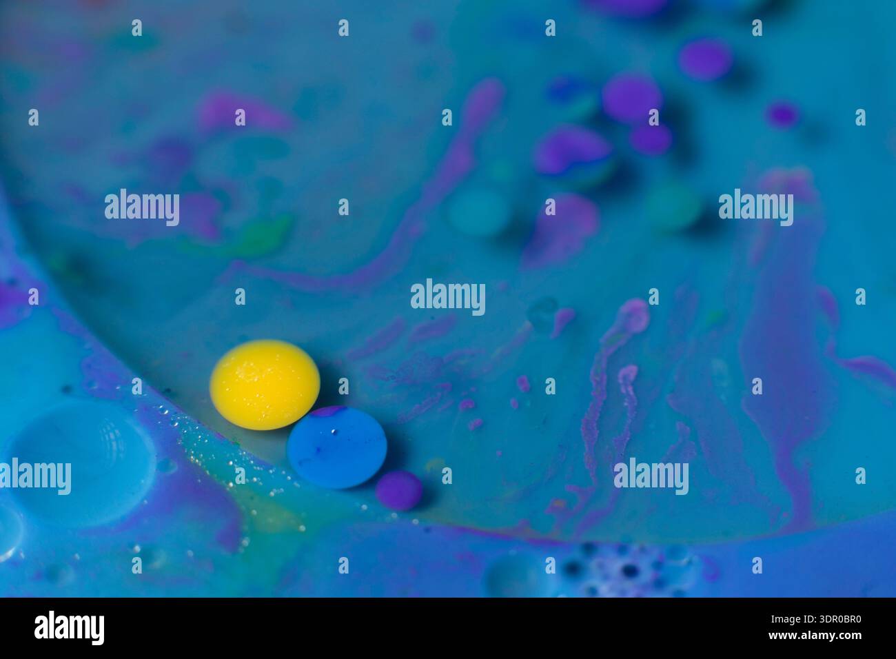 Objet irisé, coloré en liquide bleu, sphères colorées, jaune et violet, fond d'image. Banque D'Images