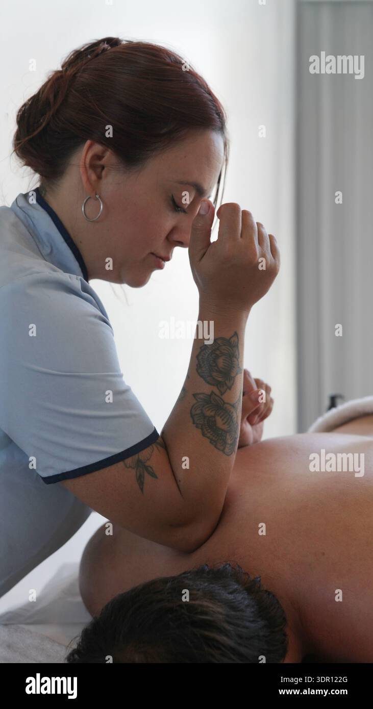Gros plan d’un massothérapeute appliquant une pression profonde au coude sur l’épaule d’un client lors d’une séance de massage thérapeutique professionnelle dans un cli intérieur Banque D'Images