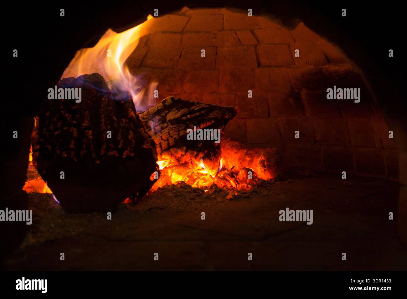 Bois de chauffage brûlant dans un four à briques avec des flammes incandescentes et des Embers chaudes à l'intérieur Banque D'Images
