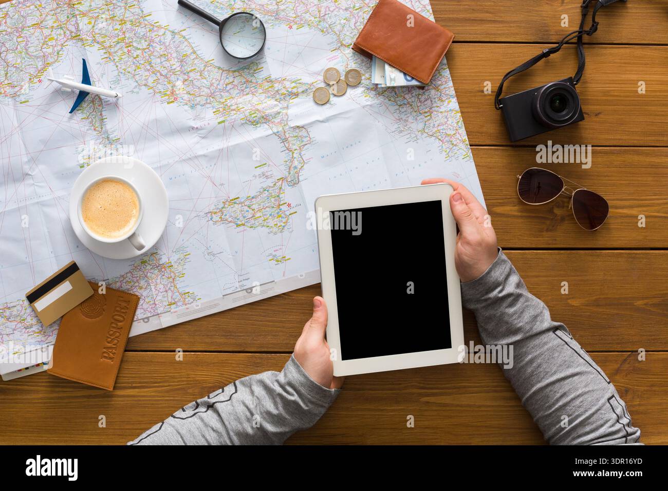 Planifier un voyage avec une tablette, un café et des documents de voyage dans une pièce lumineuse Banque D'Images