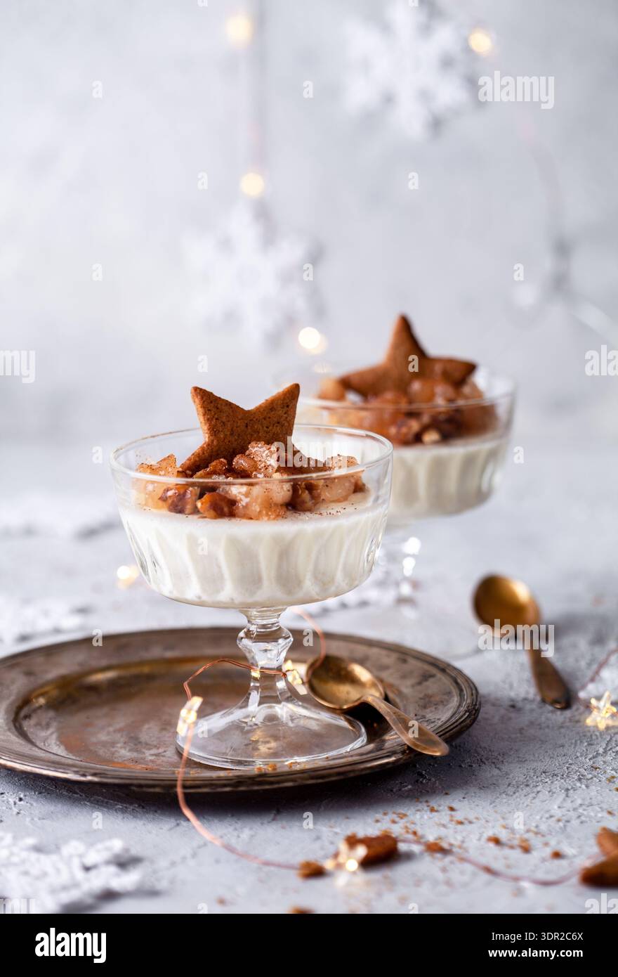 Photo de deux desserts crémeux dans des tasses en verre surmontées de fruits à noix caramélisés et d'un biscuit étoile en pain d'épices. Les lumières chaudes plateau rustique et wint confortable Banque D'Images