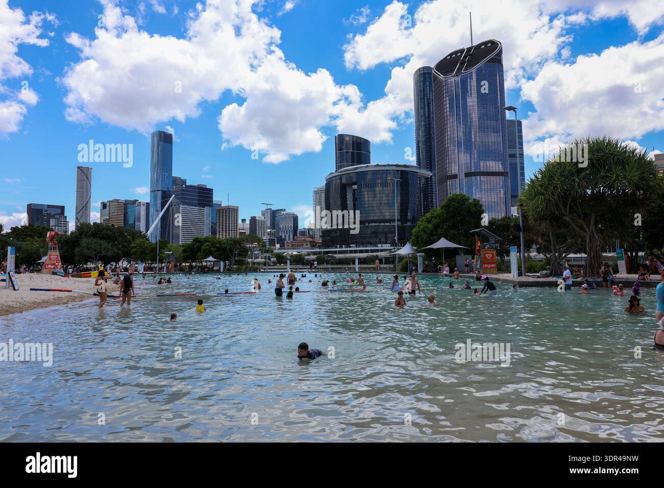 Les gens nagent et se rafraîchissent à Streets Beach dans South Bank Parklands avec l'horizon de la ville de Brisbane visible en arrière-plan lors d'une chaude journée d'été Banque D'Images
