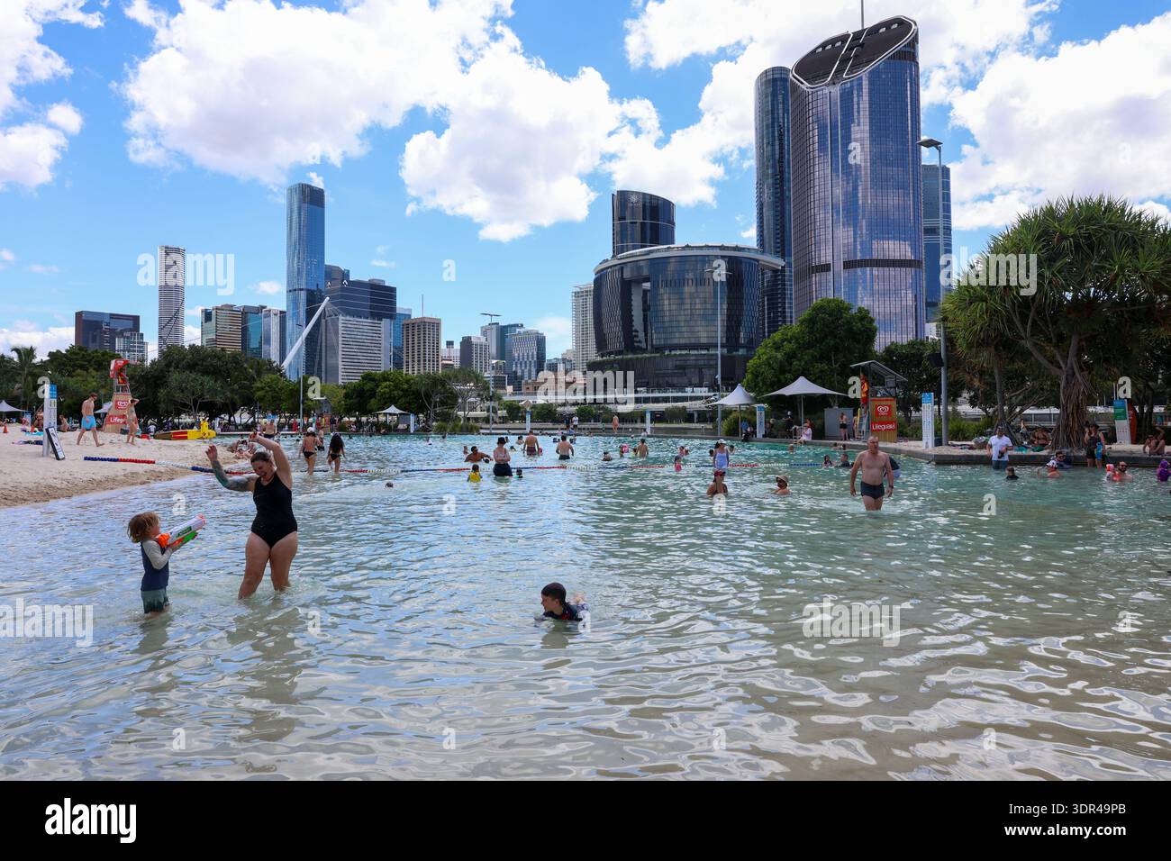 Les gens nagent et se rafraîchissent à Streets Beach dans South Bank Parklands avec l'horizon de la ville de Brisbane visible en arrière-plan lors d'une chaude journée d'été Banque D'Images
