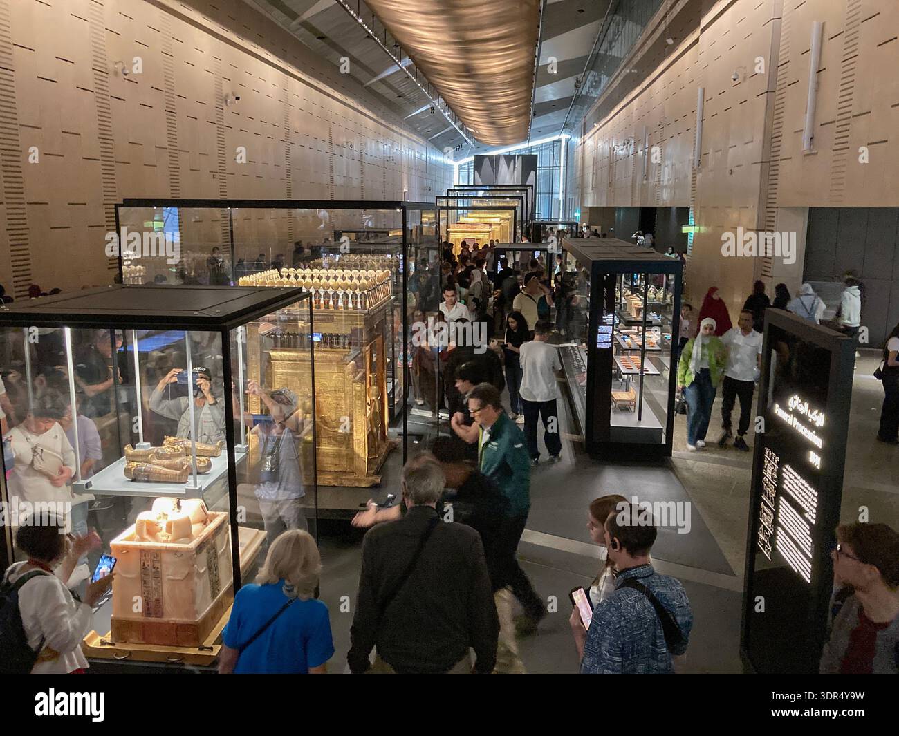 Les foules de visiteurs admirent les trésors de Tutakhamon dans les galeries dédiées du Grand Musée égyptien, Gizeh près du Caire, en Égypte. - Image de stock capturée avec un smartphone