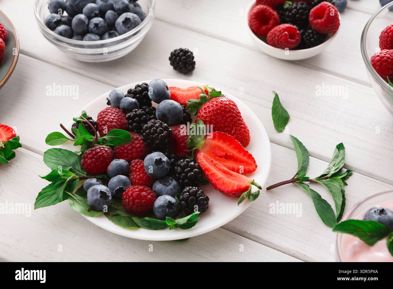 Collection de fruits frais affiché dans des bols sur une table en bois pendant un après-midi ensoleillé Banque D'Images