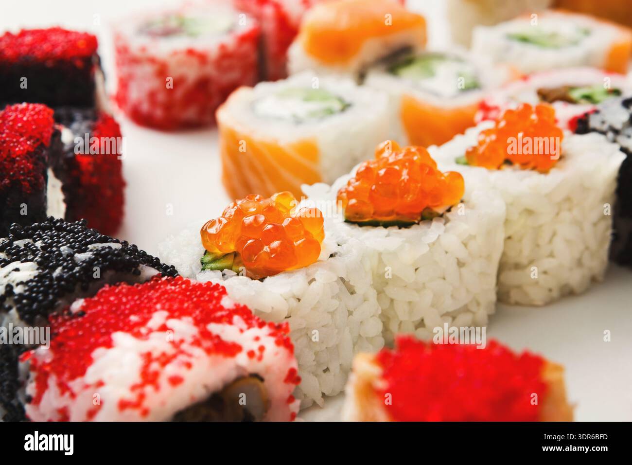 Rouleaux de sushi avec garnitures colorées disposées sur une assiette blanche pour un affichage de repas Banque D'Images