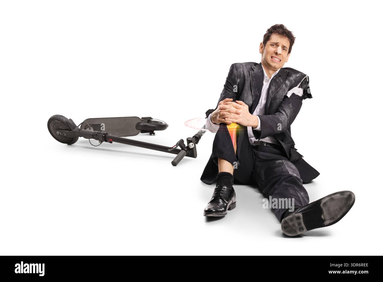 Homme d'affaires blessé dans un costume déchiré assis à côté d'un scooter électrique tombé isolé sur fond blanc Banque D'Images