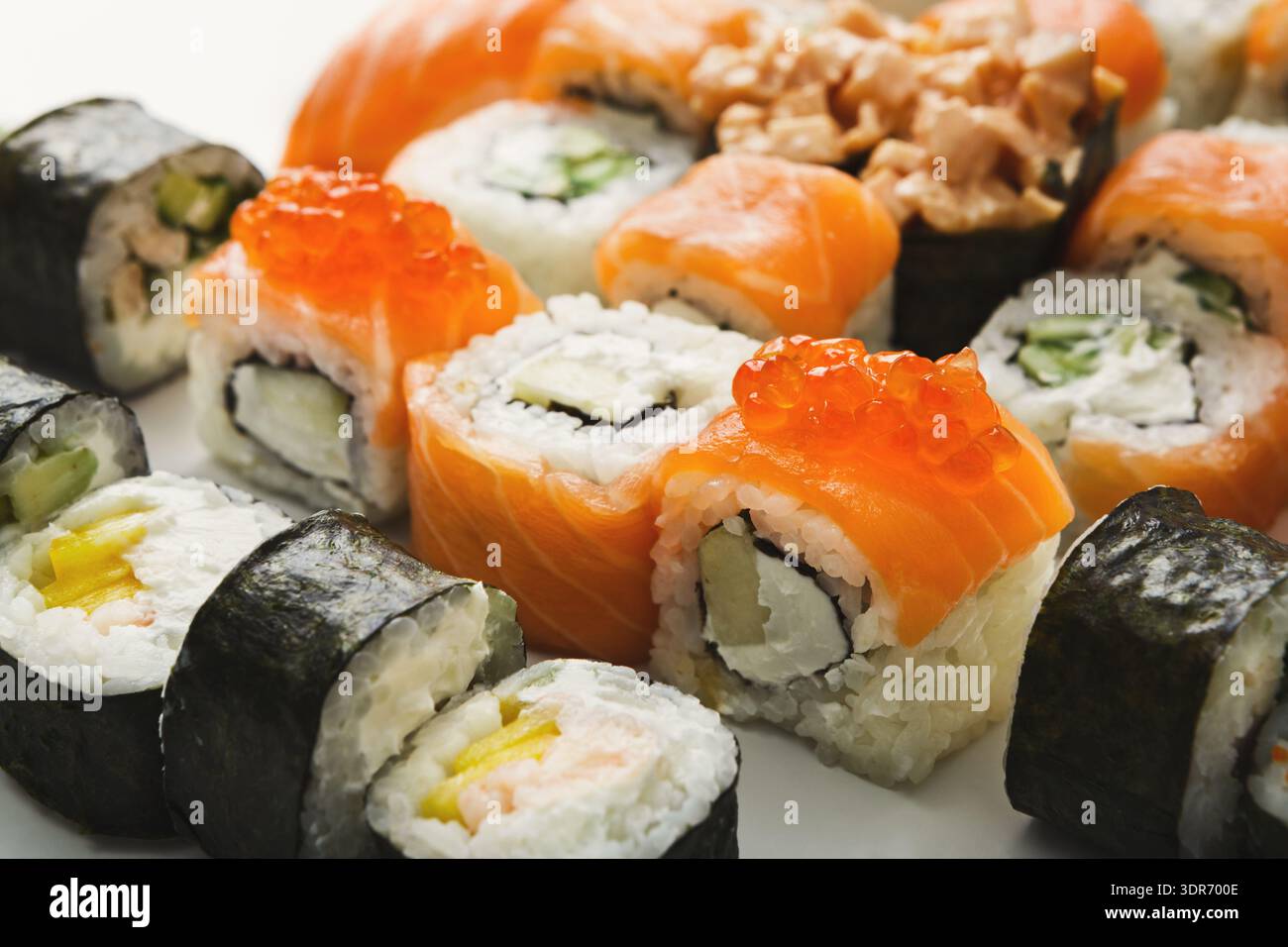 Différents types de Sushi avec des rouleaux de saumon, de crabe et de concombre sur une assiette blanche Banque D'Images