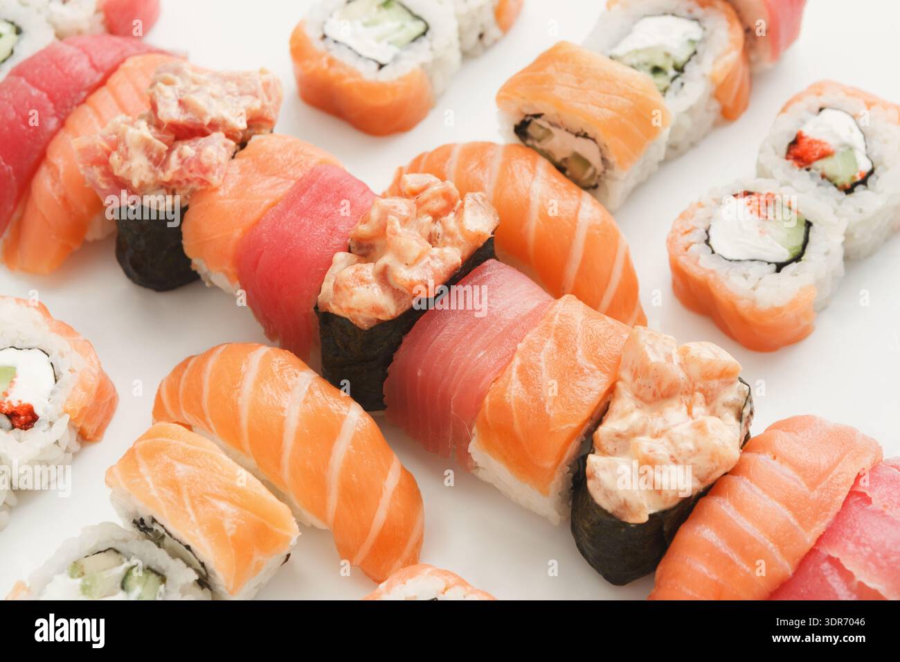 Différents types de Sushi disposés soigneusement sur une surface blanche avec différentes garnitures et garnitures Banque D'Images