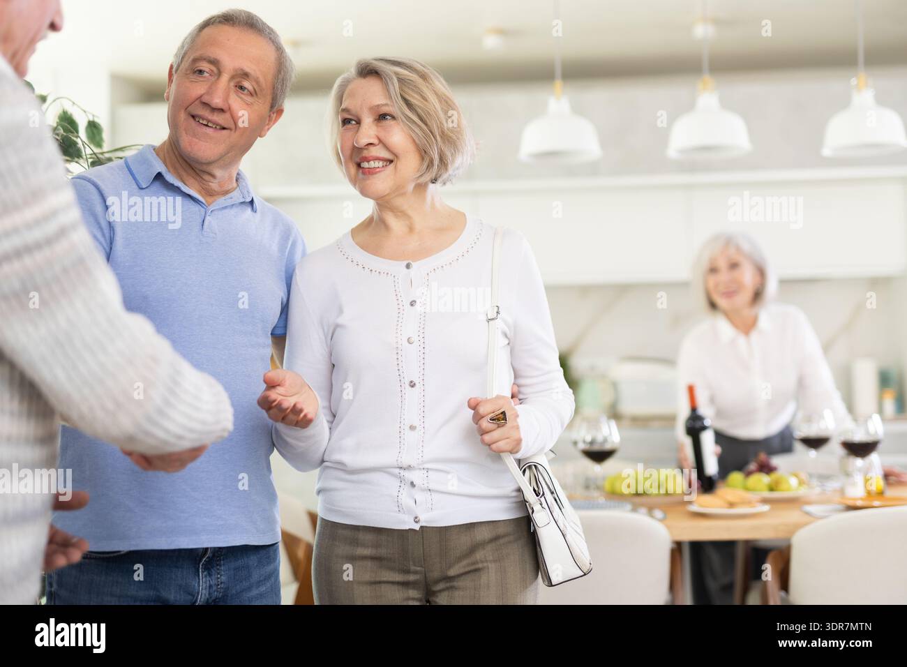 Deux couples de personnes âgées se accueillent chaleureusement alors qu'ils se réunissent pour un dîner festif de vacances à la maison Banque D'Images