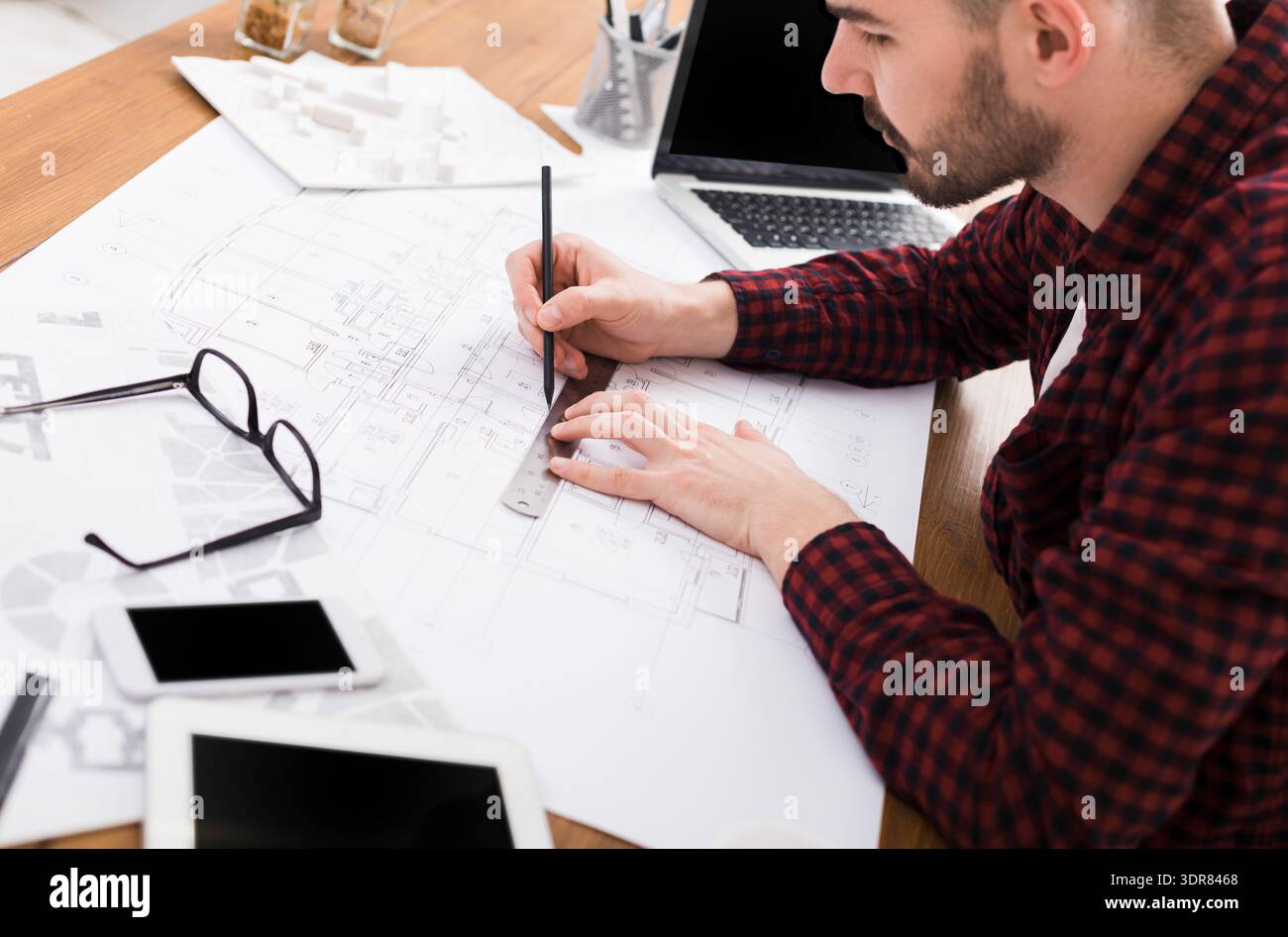 Designer crée des plans architecturaux chez Workspace avec des appareils et des outils autour de lui Banque D'Images
