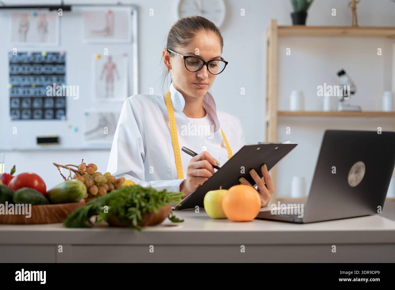 Conseillère en nutrition féminine faisant un plan de repas pendant le travail à la clinique de perte de poids. diététiste en blouse blanche écrivant prescription pour patient Banque D'Images