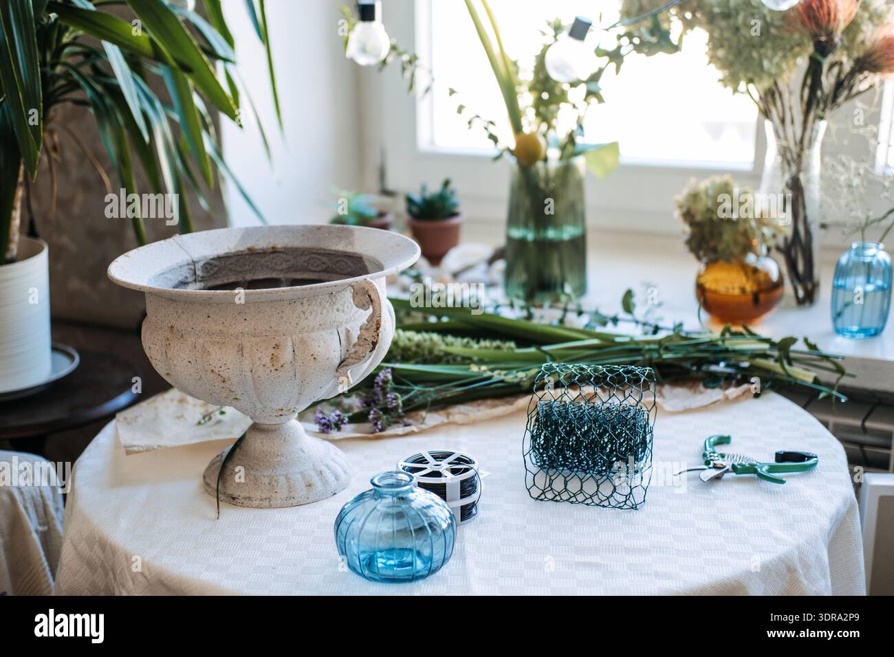 Urne blanche sur piédestal se trouve sur la table à côté de la grenouille florale et des outils de coupe. Design floral durable , techniques sans mousse, outils floraux réutilisables. Banque D'Images