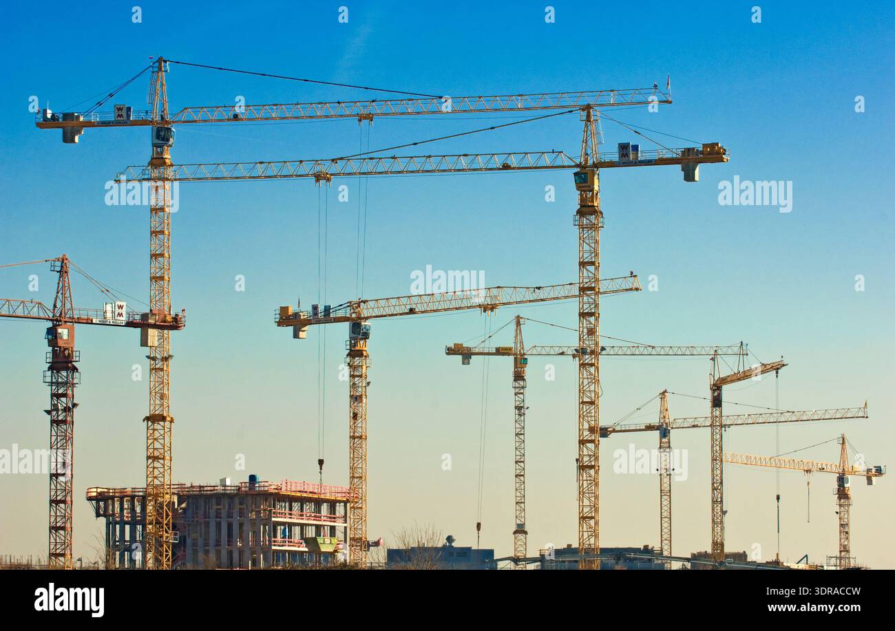Beaucoup de grues de construction sur un grand chantier avec une coquille devant un ciel sans nuages Banque D'Images