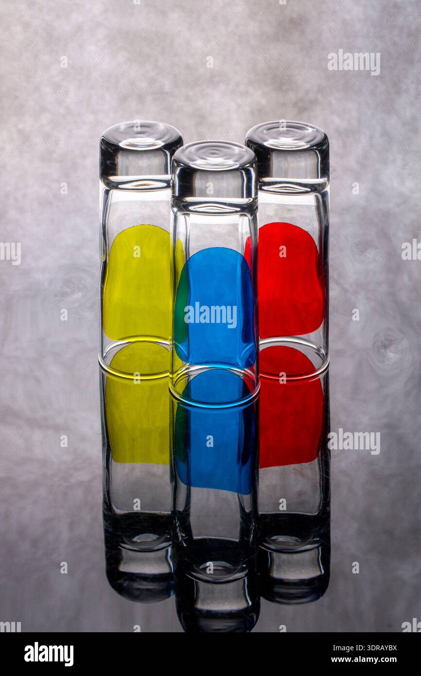 Trois gobelets en verre avec des objets jaunes, rouges et bleus à l'intérieur Banque D'Images