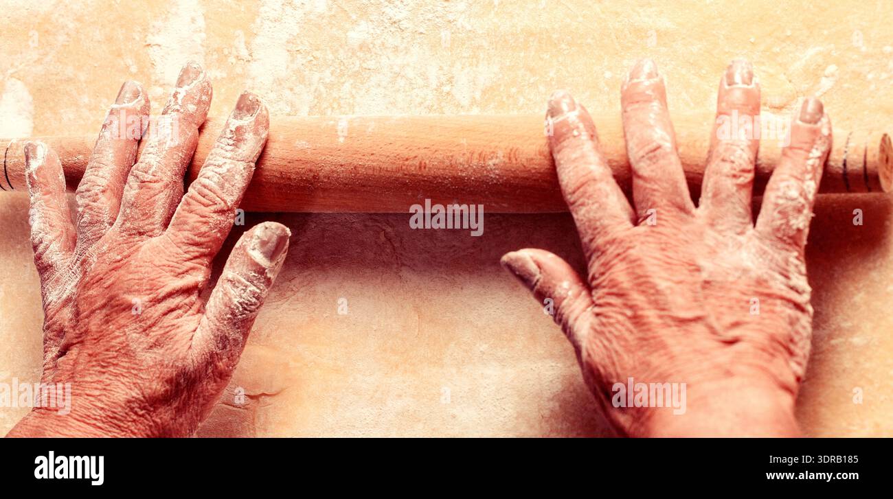 Pâte avec rouleau à pâtisserie. Femme vieilles mains roulant la pâte dans la farine avec rouleau à pâtisserie dans la boulangerie Banque D'Images