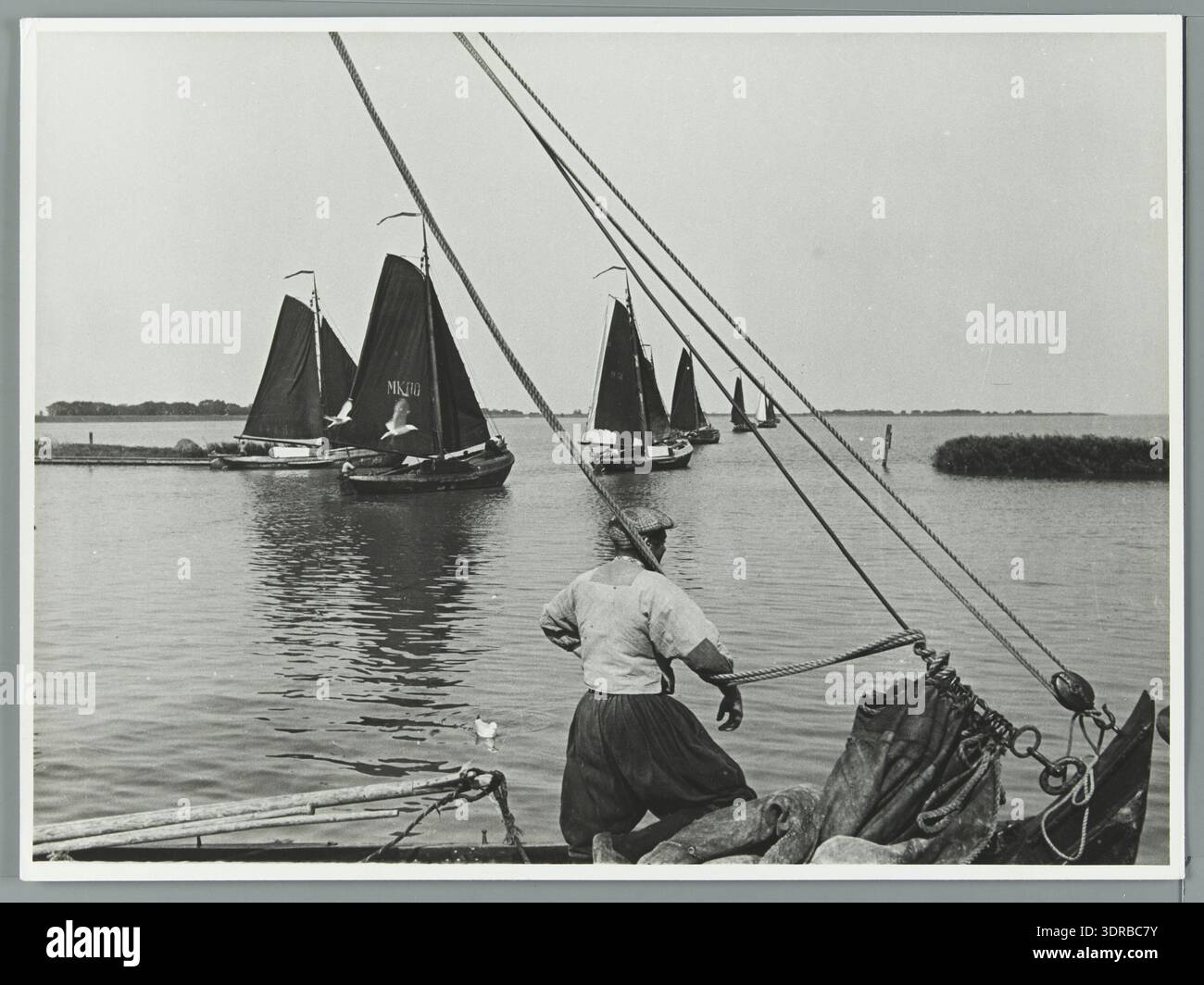 Pêcheries néerlandaises : des botteurs marqueurs revenant de la criée à Monnickendam. La photographie montre les bateaux de pêche traditionnels, l'équipage, la configuration de la voile, la structure de la coque, les filets de pêche, navigation maritime, eaux côtières, pratiques de pêche néerlandaises du début du XXe siècle et approche portuaire. Il documente les opérations maritimes, la conception des navires, le transport du poisson et le rôle des botteurs Marker dans la pêche locale, fournissant une référence historique à la pêche côtière néerlandaise et au commerce des petits bateaux. Banque D'Images