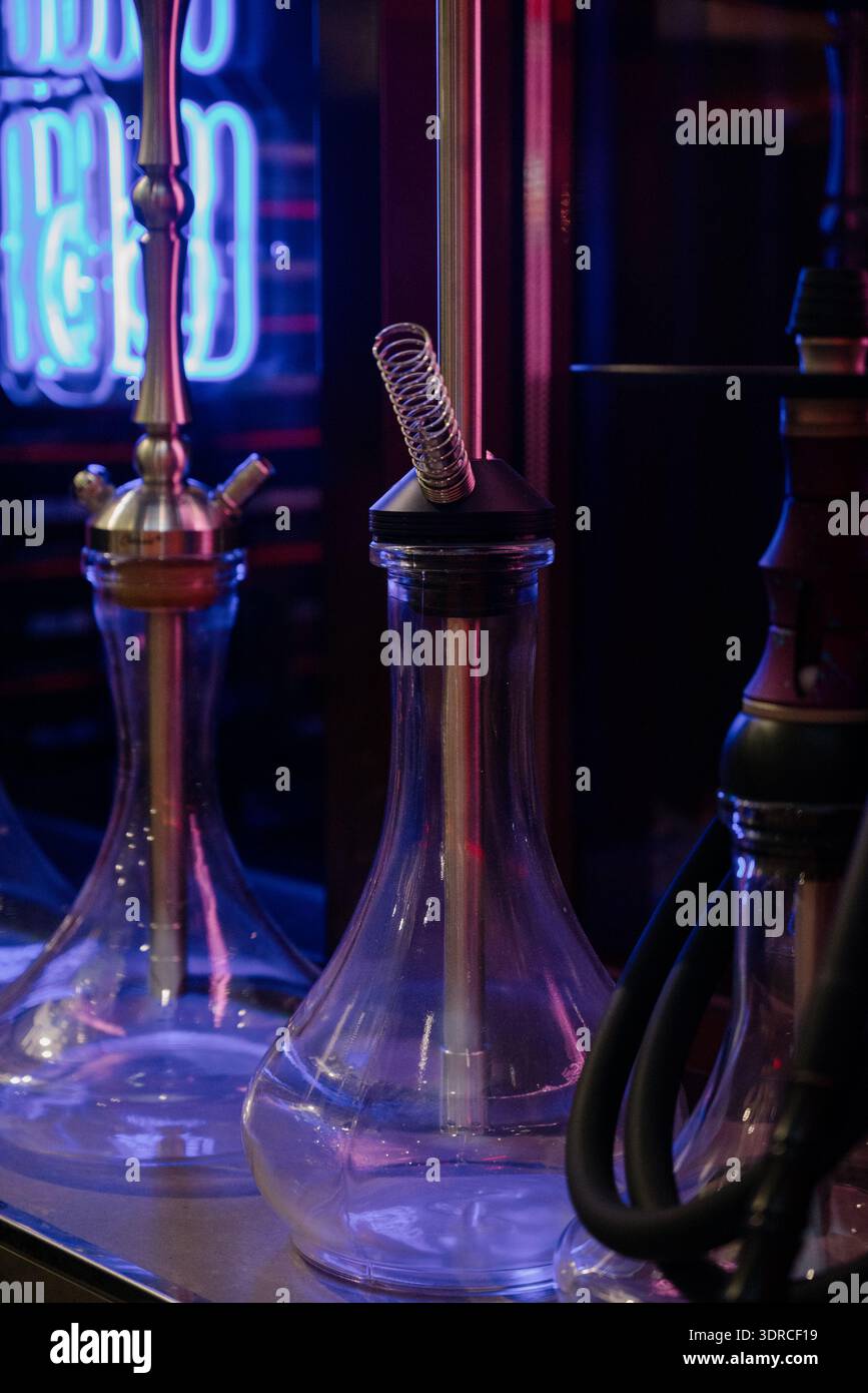 Hookahs en verre sur un comptoir de bar dans une discothèque avec éclairage au néon.hookahs modernes en verre et en métal dans un salon de hookah avec néon bleu Banque D'Images