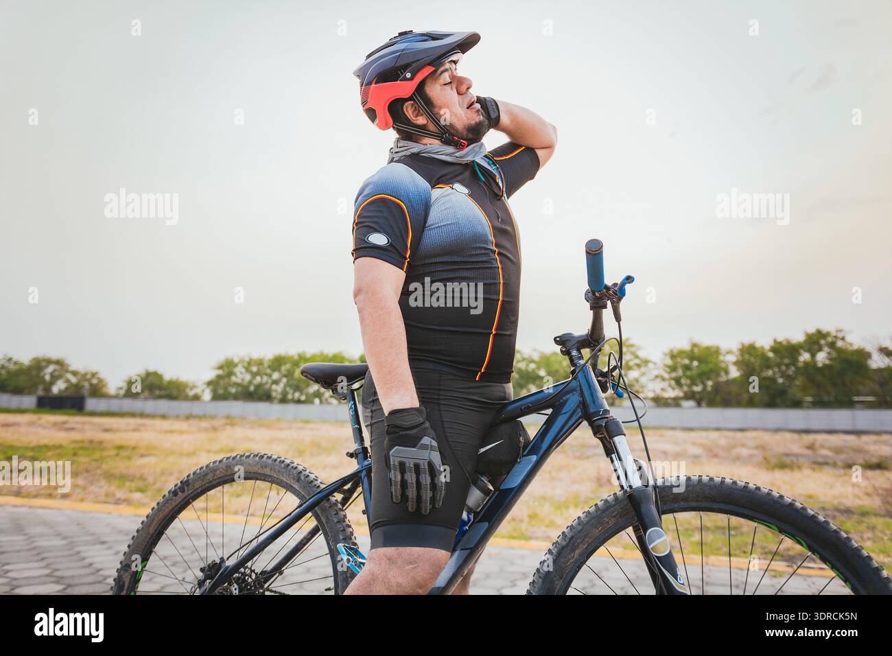 Cycliste masculin avec douleur au cou à l'extérieur. Cycliste sportif souffrant de douleurs au cou lors de la conduite d'un vélo Banque D'Images