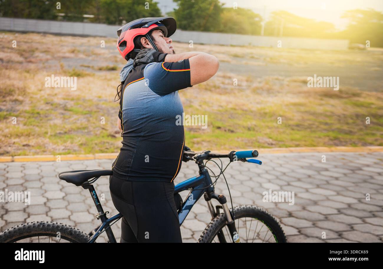 Cycliste sportif souffrant de douleurs au cou lors de la conduite d'un vélo. Cycliste masculin avec douleur au cou à l'extérieur Banque D'Images