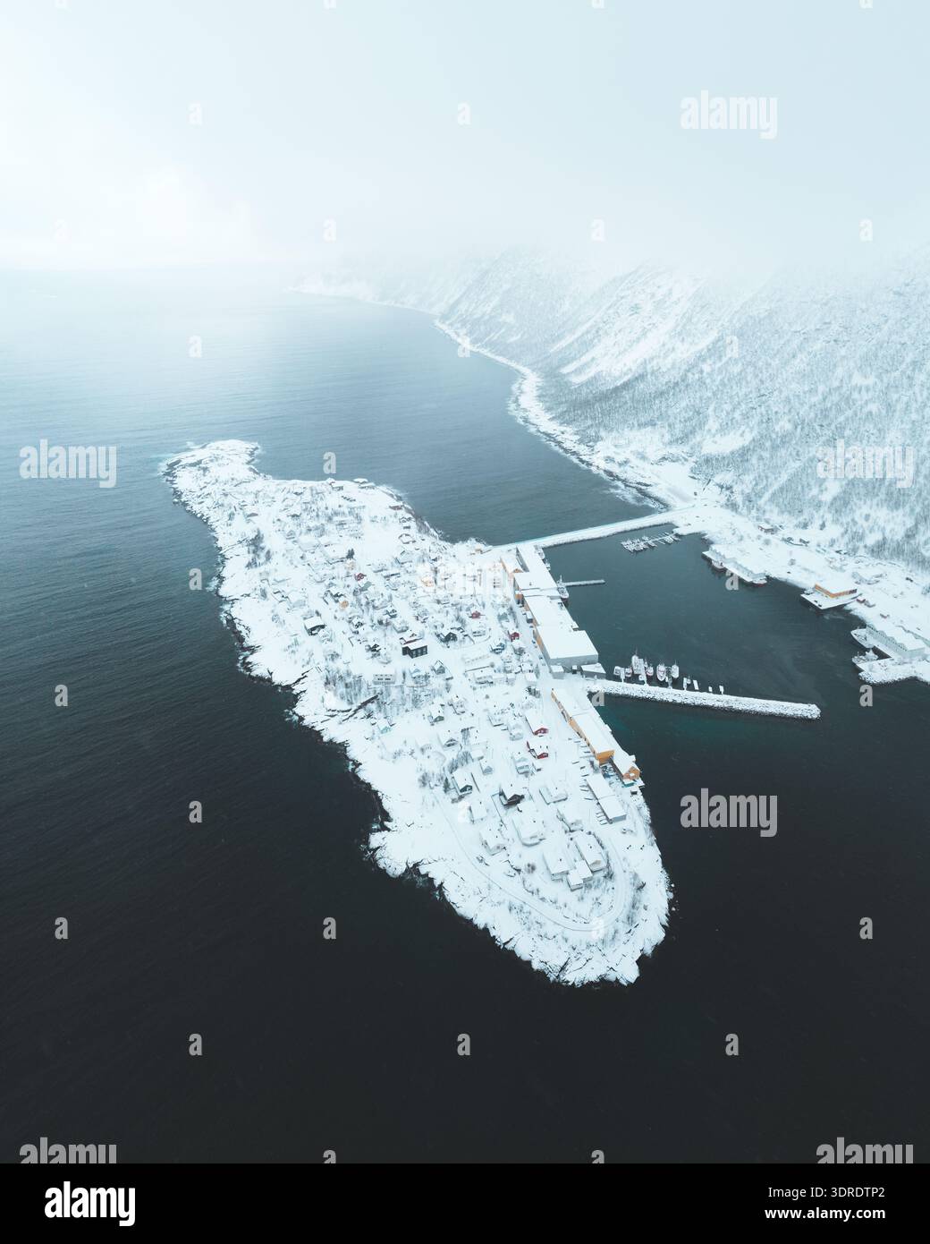 Vue aérienne d'un village enneigé niché sur une petite île à côté des fjords, vu d'en haut à Husøy, Vestfold, Norvège. Banque D'Images