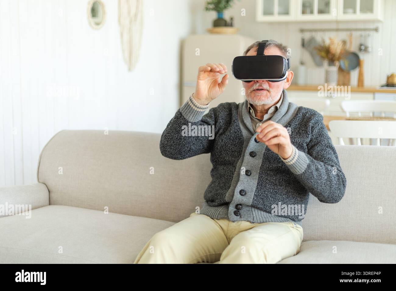 Homme senior mature excité portant à l'aide du casque de lunettes de réalité virtuelle Metaverse VR à la maison. Grand-père touchant l'air pendant la VR Banque D'Images