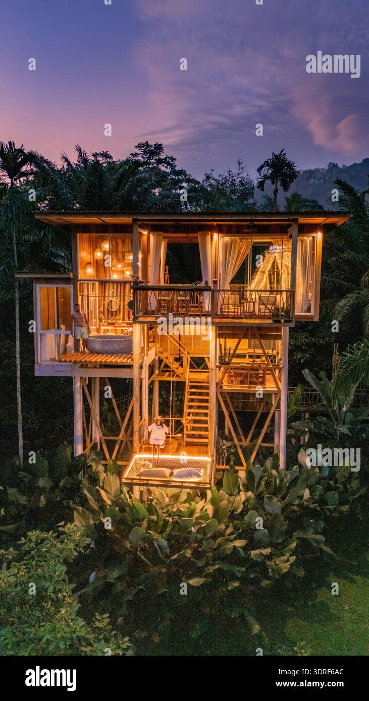 Charmante maison en bambou illuminée au crépuscule entourée de verdure luxuriante à Bali, Thaïlande Banque D'Images