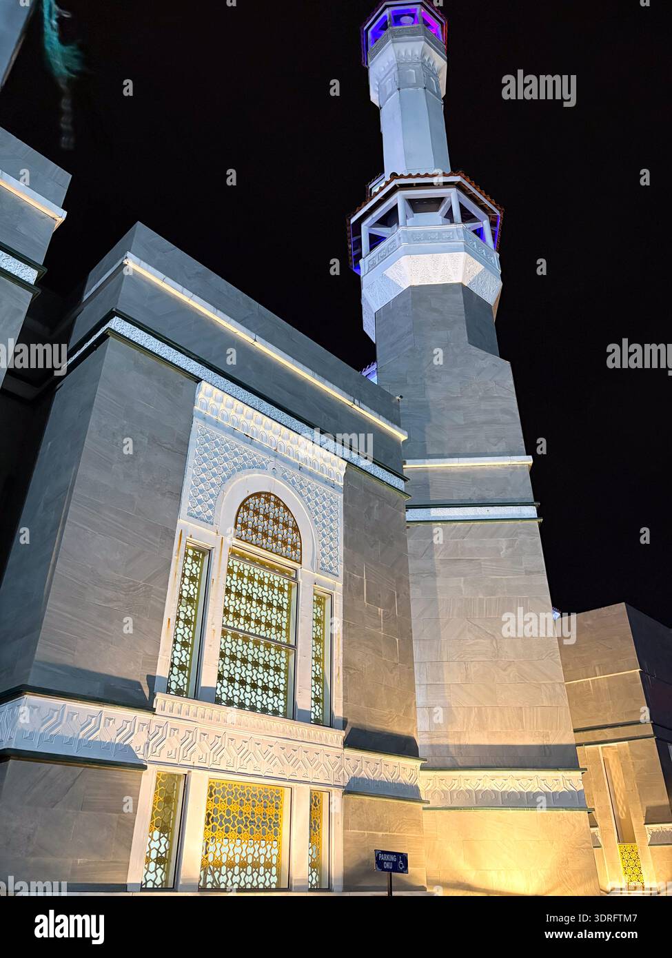 Kelantan, Malaisie - 7 février 2026. Une perspective nocturne d'une mosquée moderne avec un grand minaret blanc illuminé et des motifs géométriques complexes - Image de stock capturée avec un smartphone