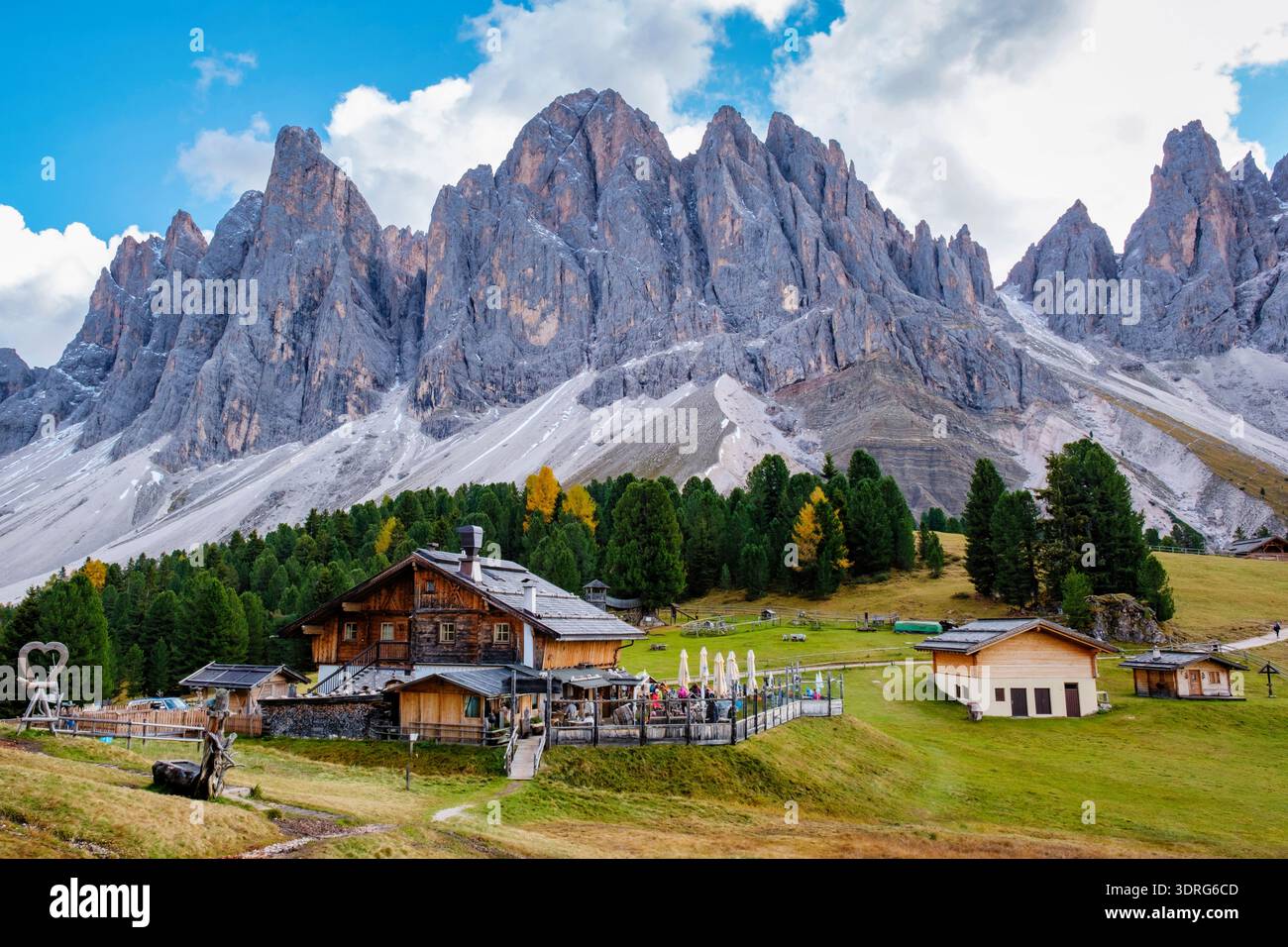 Les majestueuses Dolomites s'élèvent au-dessus de charmants chalets à Val Di Funes, en Italie, sous un ciel spectaculaire Banque D'Images