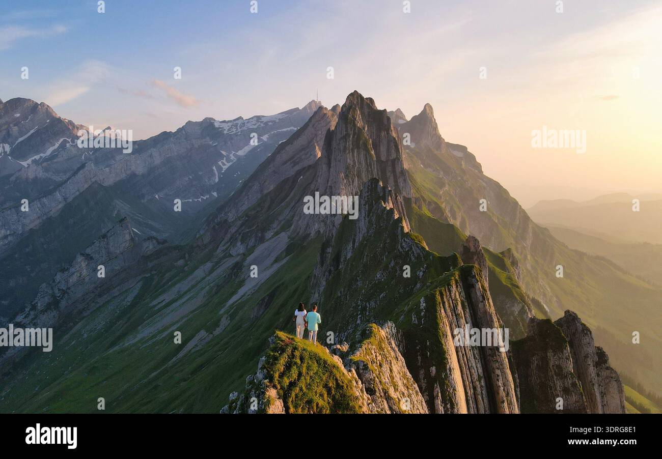 Vue époustouflante sur le coucher du soleil depuis un sommet de montagne dans les Alpes suisses avec deux randonneurs profitant de la nature Banque D'Images
