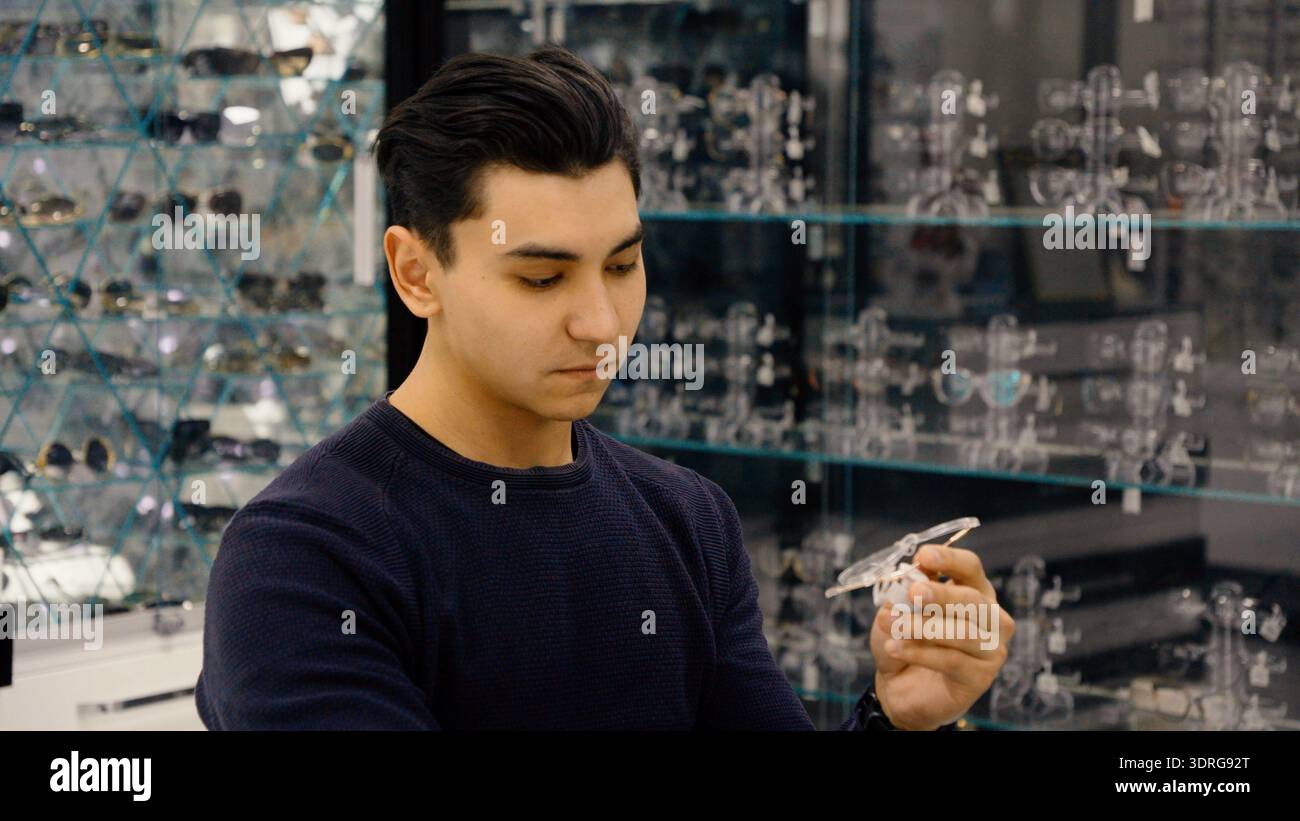 Homme regardant des lunettes dans sa main dans un magasin d'optique Banque D'Images