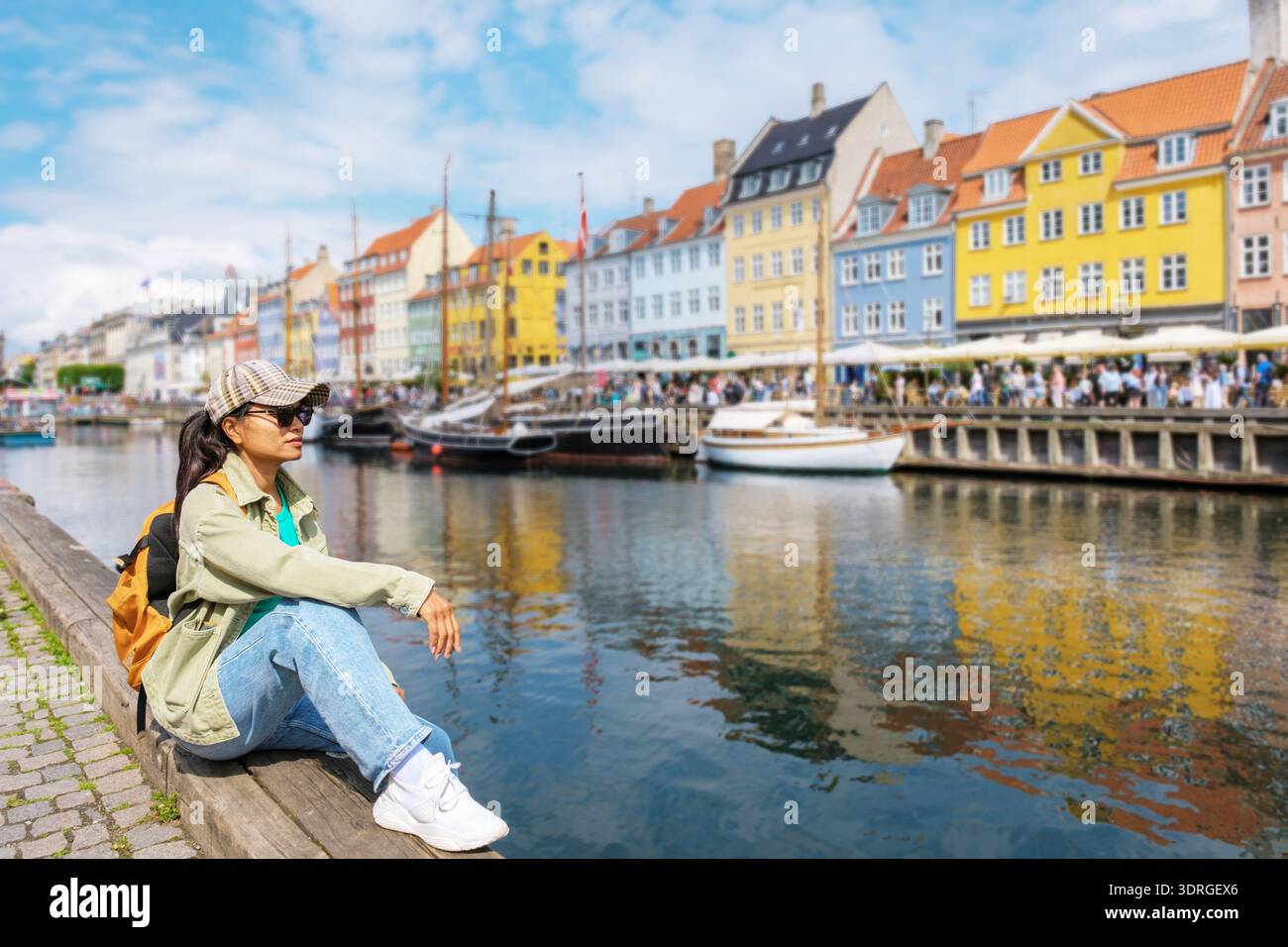 Charmant front de mer à Nyhavn, Copenhague, Danemark avec des bâtiments colorés et un touriste détendu Banque D'Images