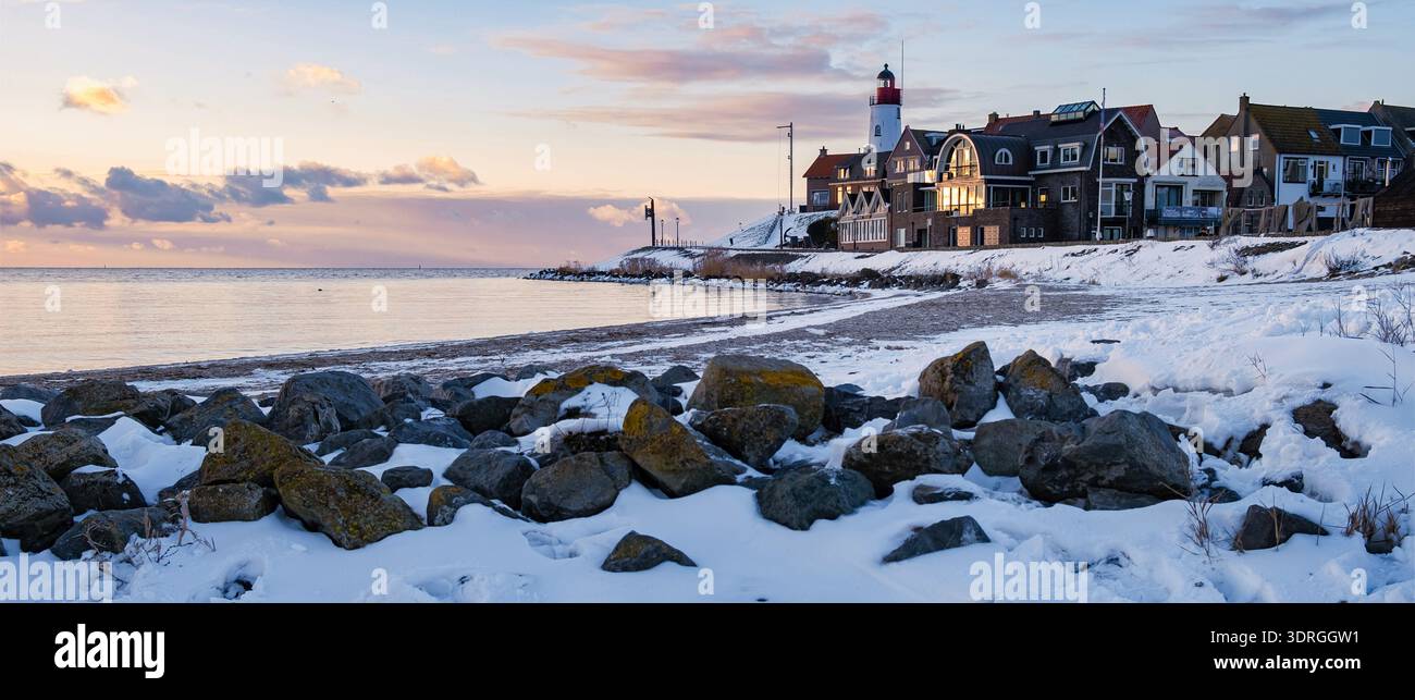 Coucher de soleil d'hiver illumine village balnéaire idyllique avec phare par les eaux calmes Banque D'Images