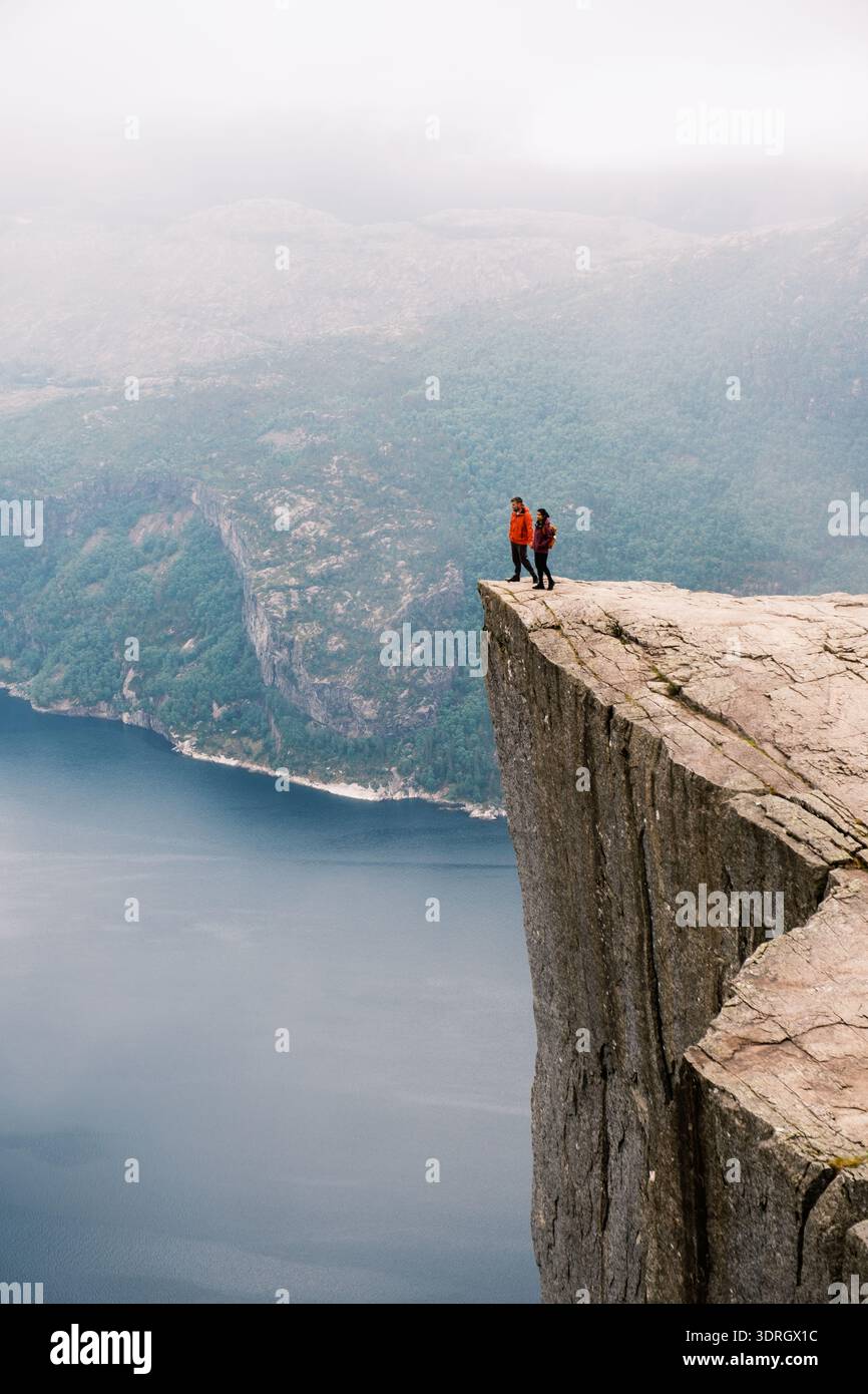 Randonneurs debout sur le bord de la falaise Preikestolen en Norvège surplombant une vue imprenable sur le fjord Banque D'Images