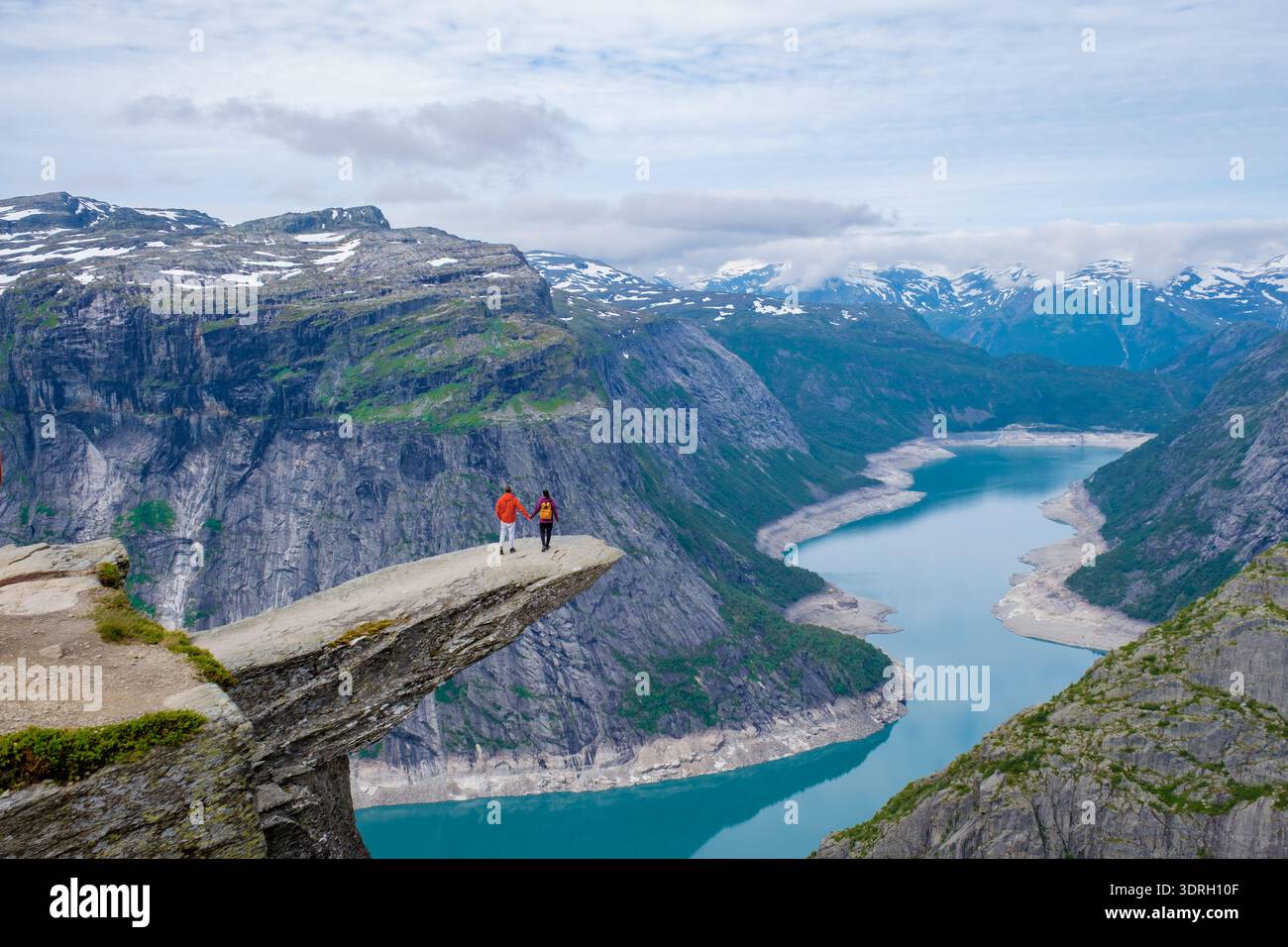 Vue imprenable depuis le bord de la falaise en Norvège mettant en vedette les randonneurs contre le paysage majestueux des fjords Banque D'Images